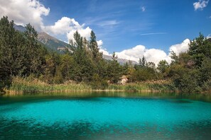 A clear lake surrounded by trees and mountains.