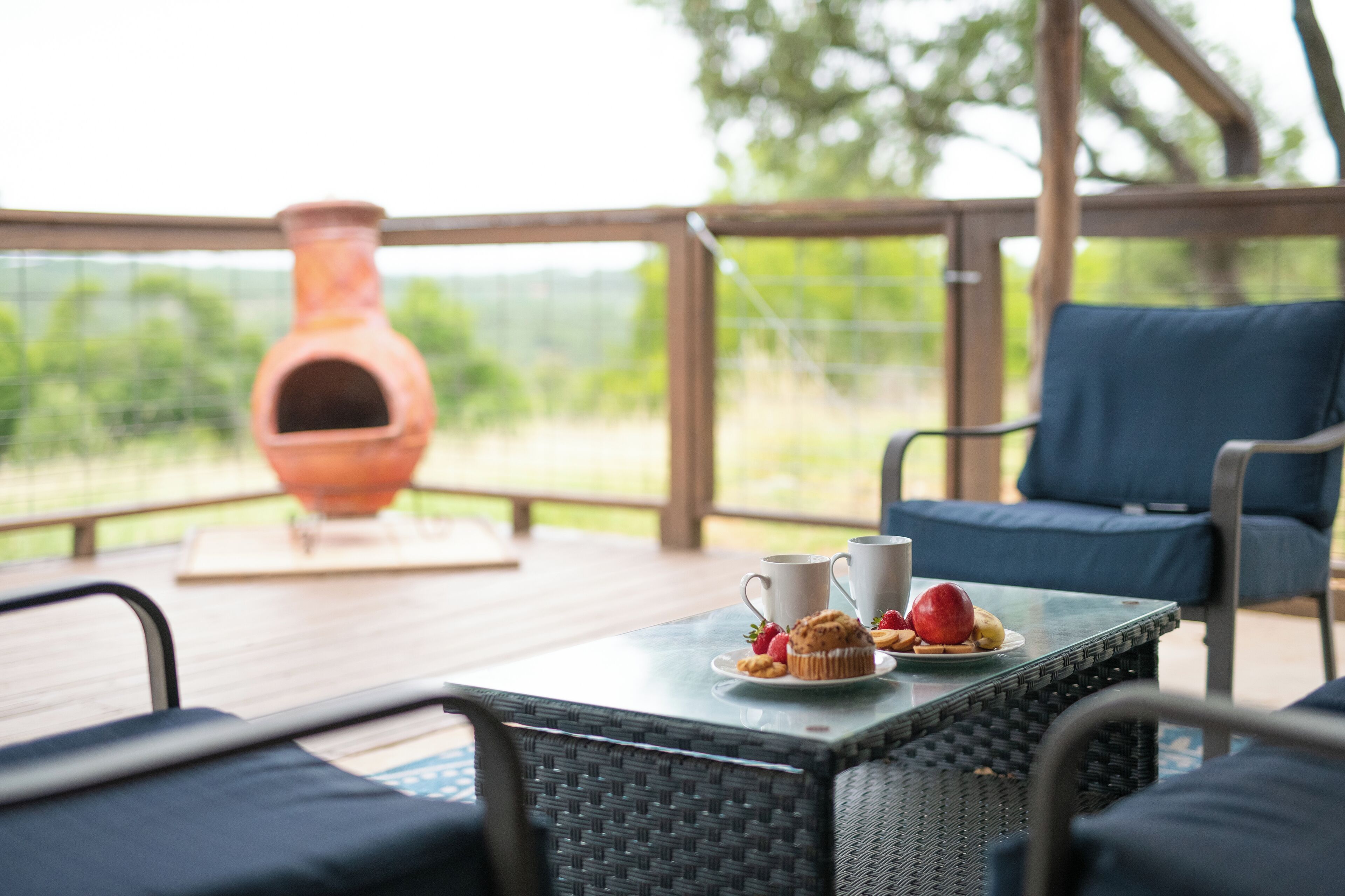 A covered patio with wicker furniture, a table with a plate of food, and a large clay pot.