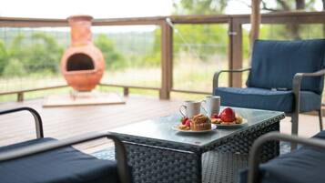 A covered patio with wicker furniture, a table with a plate of food, and a large clay pot.