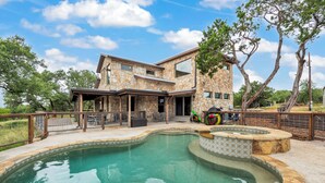 Una casa moderna con fachada de piedra, piscina y zona de patio.