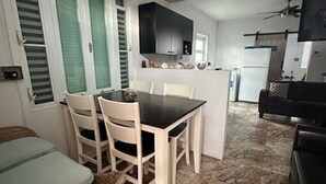 A compact kitchen with a dining area, a ceiling fan, and a TV mounted on the wall. - Wake Up to Ocean Views: Your Puerto Rico Paradise Awaits! (Yabucoa)