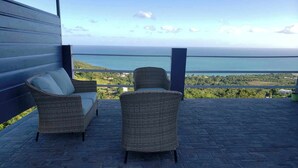 A balcony with wicker furniture and a view of the ocean. - Wake Up to Ocean Views: Your Puerto Rico Paradise Awaits! (Yabucoa)