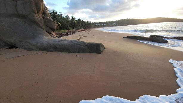 A sandy beach with large rocks and waves. - Wake Up to Ocean Views: Your Puerto Rico Paradise Awaits! (Yabucoa)