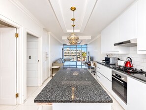 A modern kitchen with a central island, white cabinetry, and a view to the outside.
