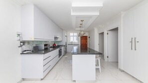 A modern kitchen with white cabinetry, a central island, and a pendant light.