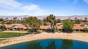 A residential area with houses, a swimming pool, and a desert landscape in the background. - Peaceful Waterfront Getaway (pet-friendly) (Palm Desert)