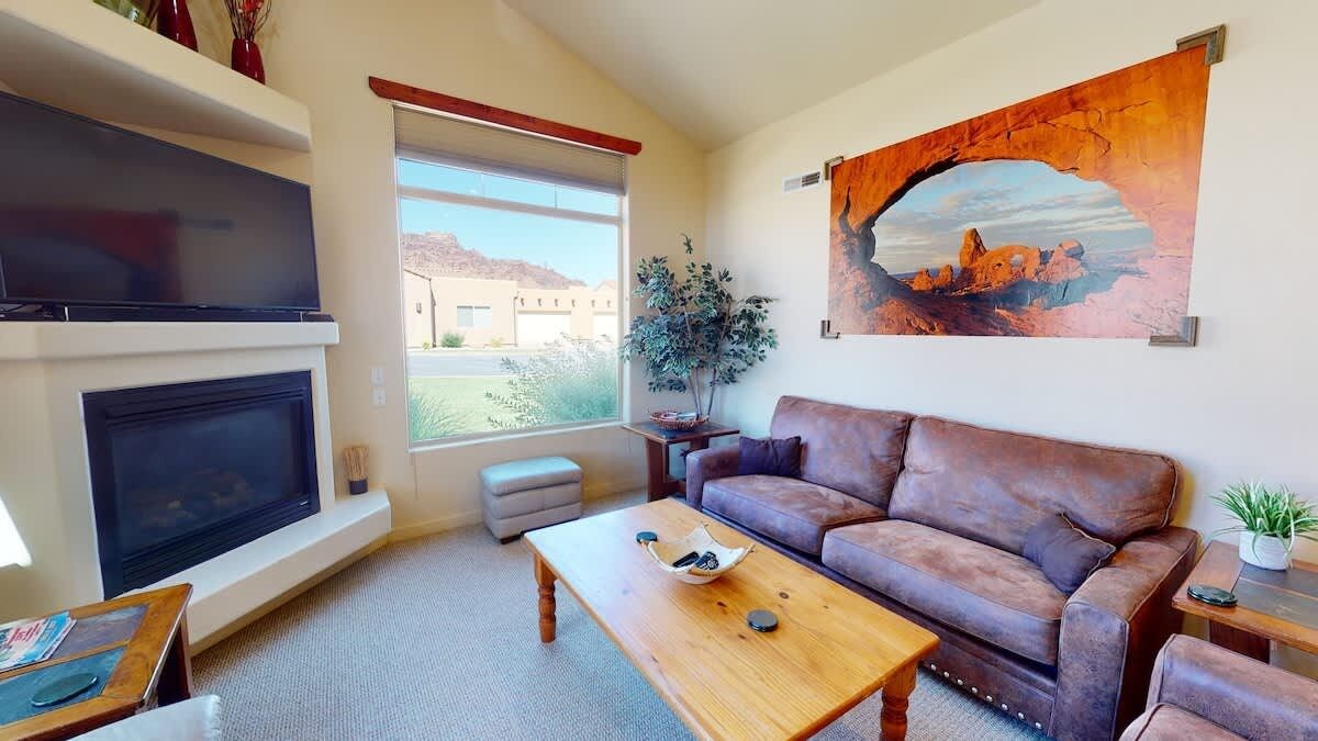 Een woonkamer met een open haard, een bank, een salontafel en een groot raam.