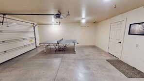A room with a ping pong table, a white door, and a projector mounted on the ceiling.