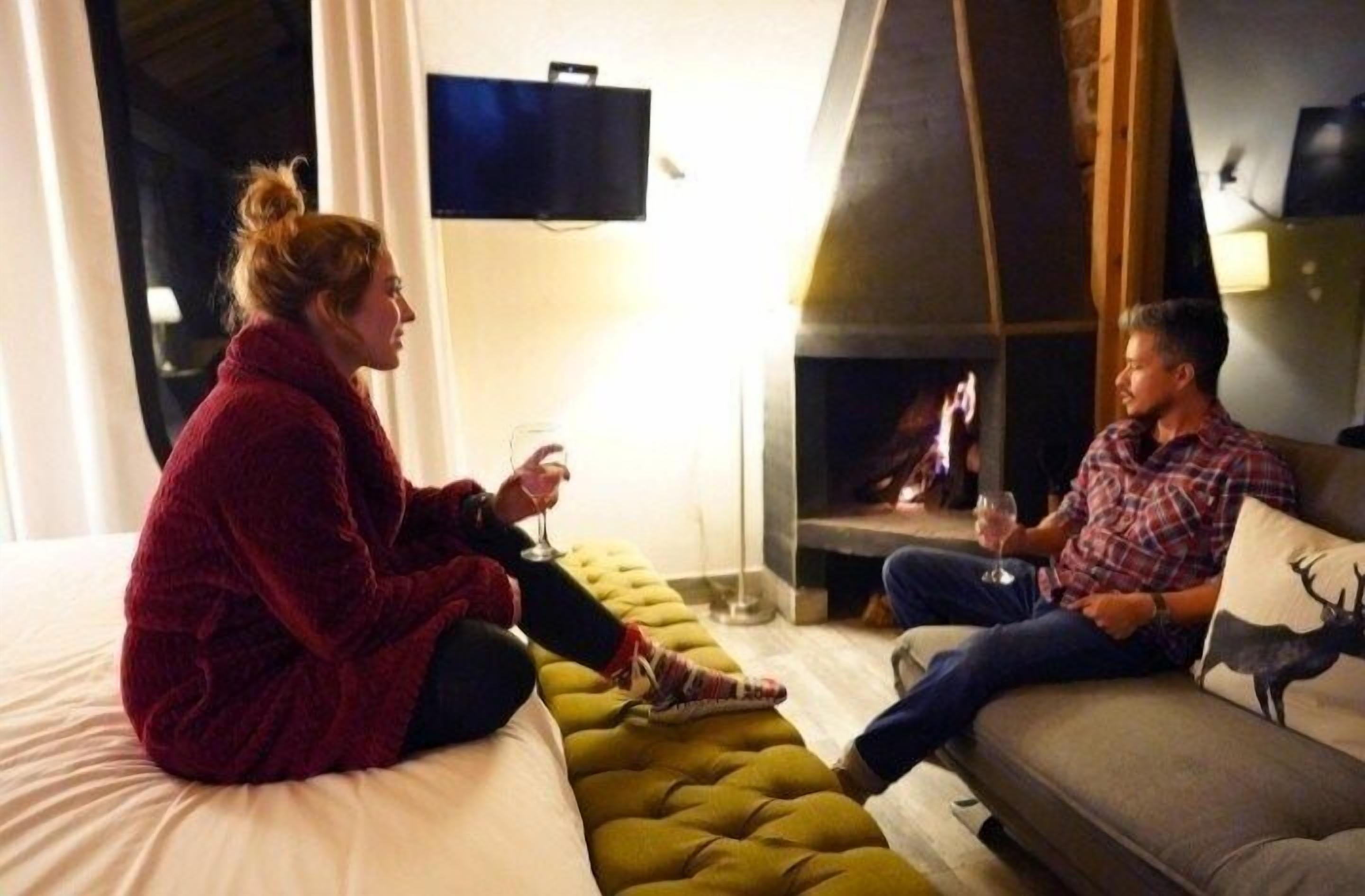 A room with a bed, a sofa, and a fireplace.