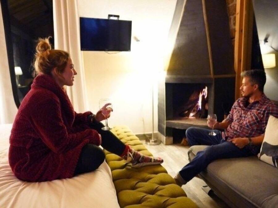 A room with a bed, a sofa, and a fireplace.