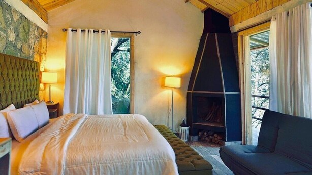 A cozy bedroom with a large bed, a fireplace, and a sofa. - Cabaña El Encino II en Real del Monte (Mineral del Monte)