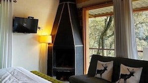 A cozy room with a bed, a sofa, a fireplace, and a television. - Cabaña El Encino II en Real del Monte (Mineral del Monte)
