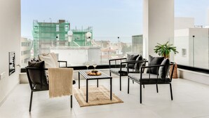 Una sala de estar moderna con un ventanal grande, mobiliario negro y una zona de comedor.