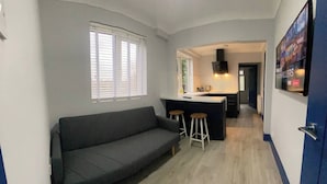Een compacte woonruimte met een bank, een kitchenette en een barretje.