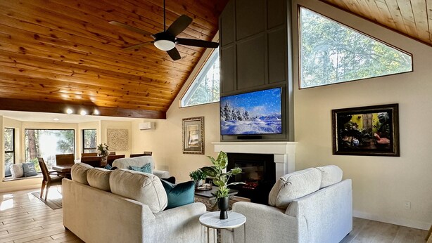 A cozy living room with a fireplace, comfortable seating, and large windows offering natural light and views.
