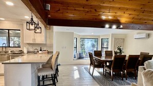 A spacious kitchen with a large island, wooden ceiling, and a dining area with a view of the outdoors.