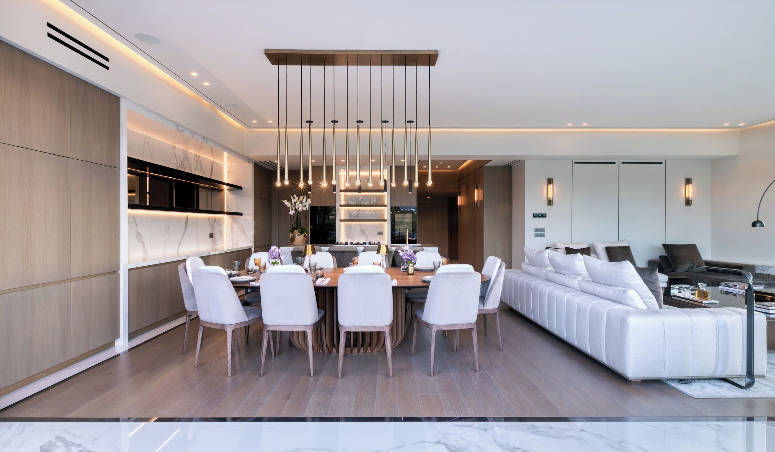 Una sala de estar moderna con comedor, que incluye un conjunto de sofá, una mesa de comedor con sillas y una lámpara colgante.
