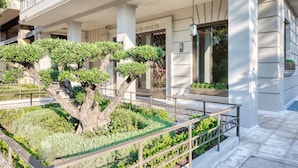 Un edificio moderno con un árbol grande en el centro, rodeado de follaje cuidado.