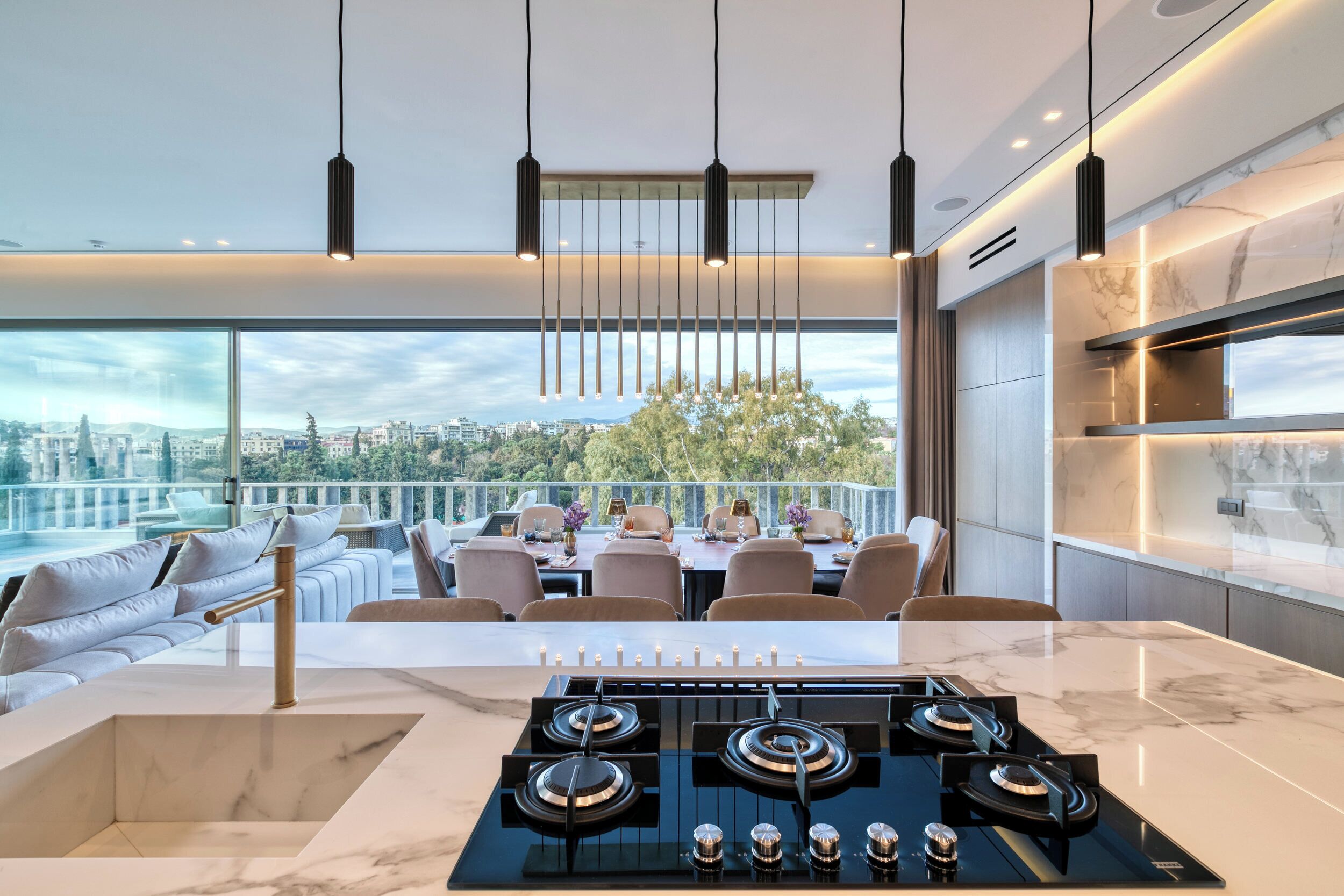 A modern kitchen with a large island, a dining area with a view, and a cityscape in the background.