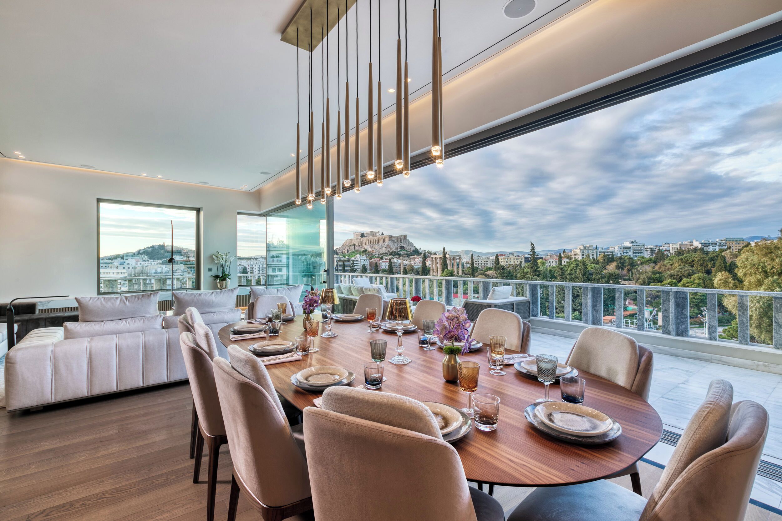 Un comedor moderno con una mesa de madera preparada para seis personas, con vista a una ciudad y a un edificio histórico.