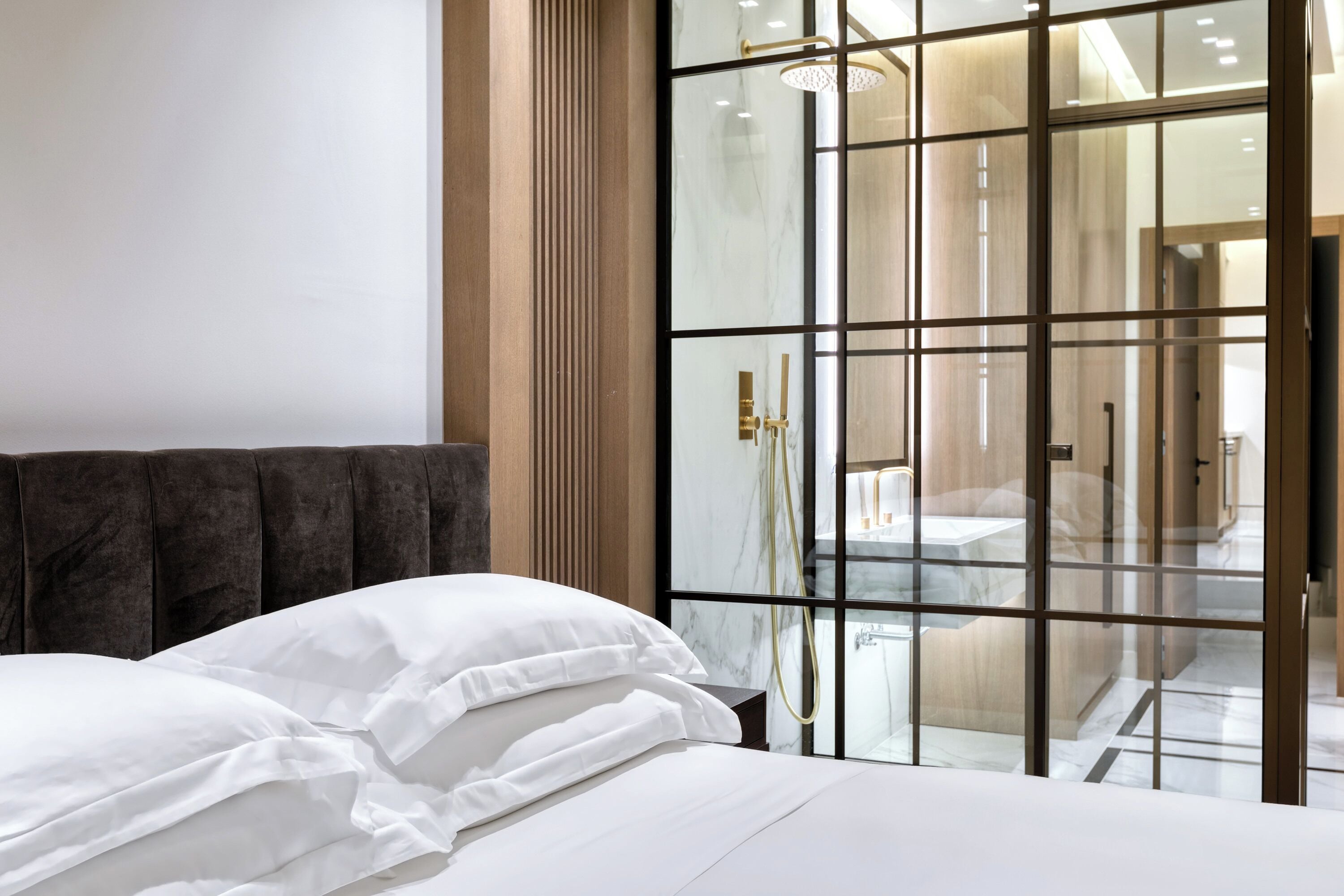 Una habitación de hotel moderna con una cama grande, una pared divisoria de vidrio y vistas al baño.