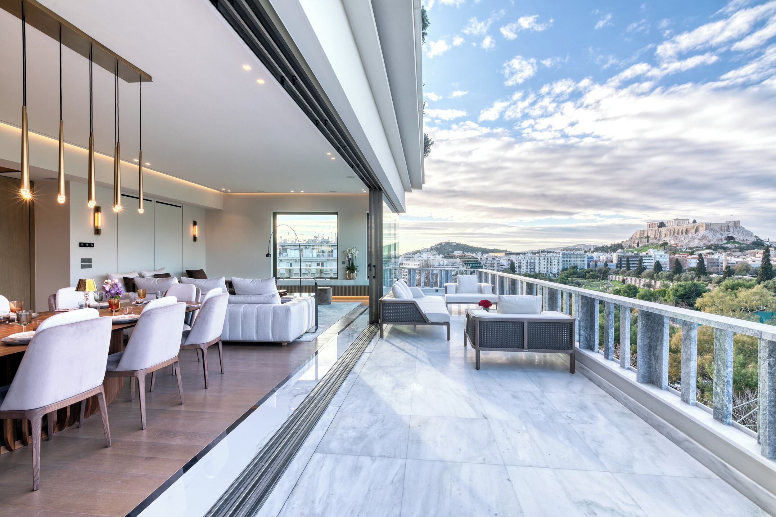 Ein modernes Wohnzimmer mit Essbereich, großen Fenstern und einem Balkon mit Blick auf die Stadt.
