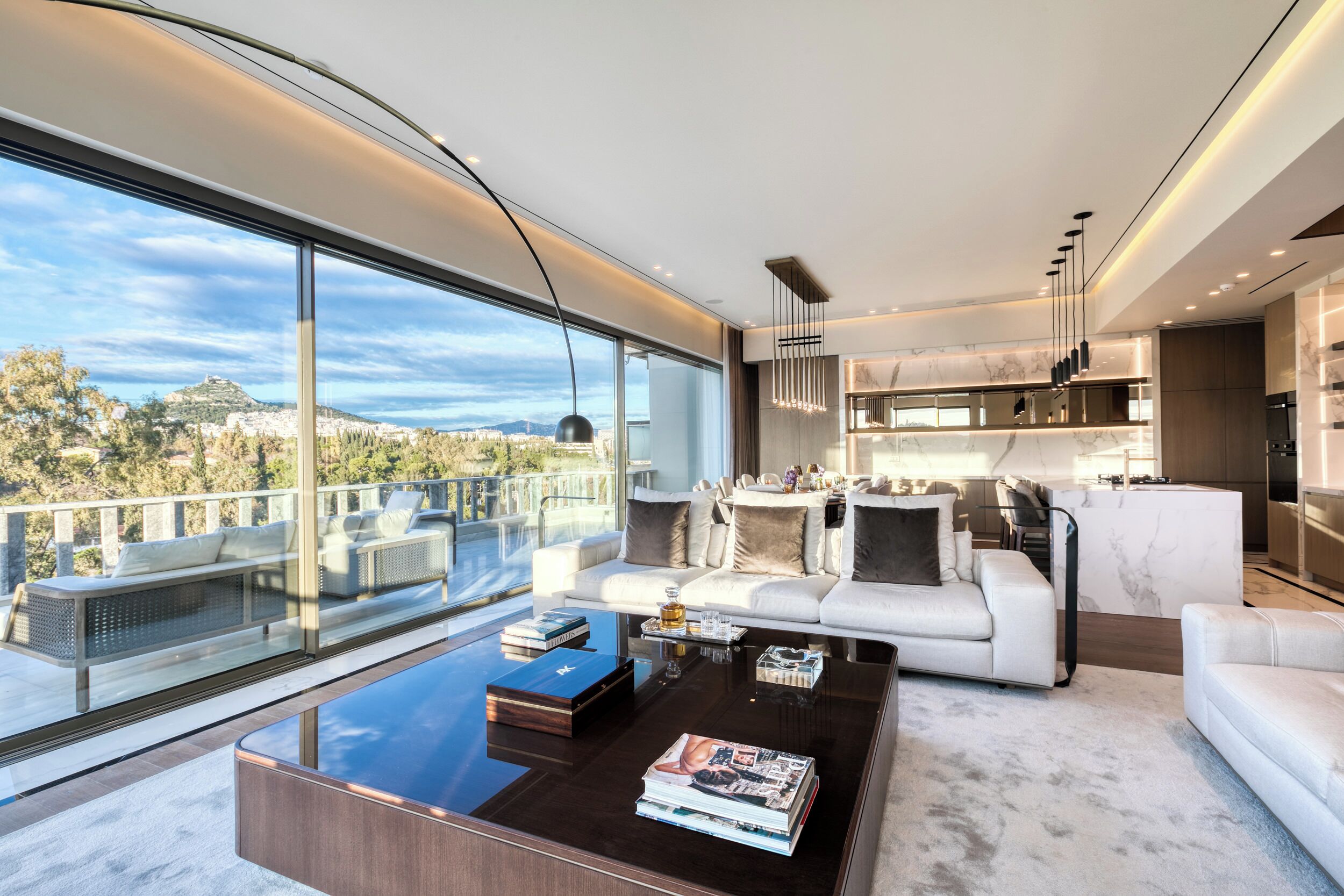 Un salon moderne doté d’une grande baie vitrée, d’un canapé, d’une table basse et d’un coin cuisine.