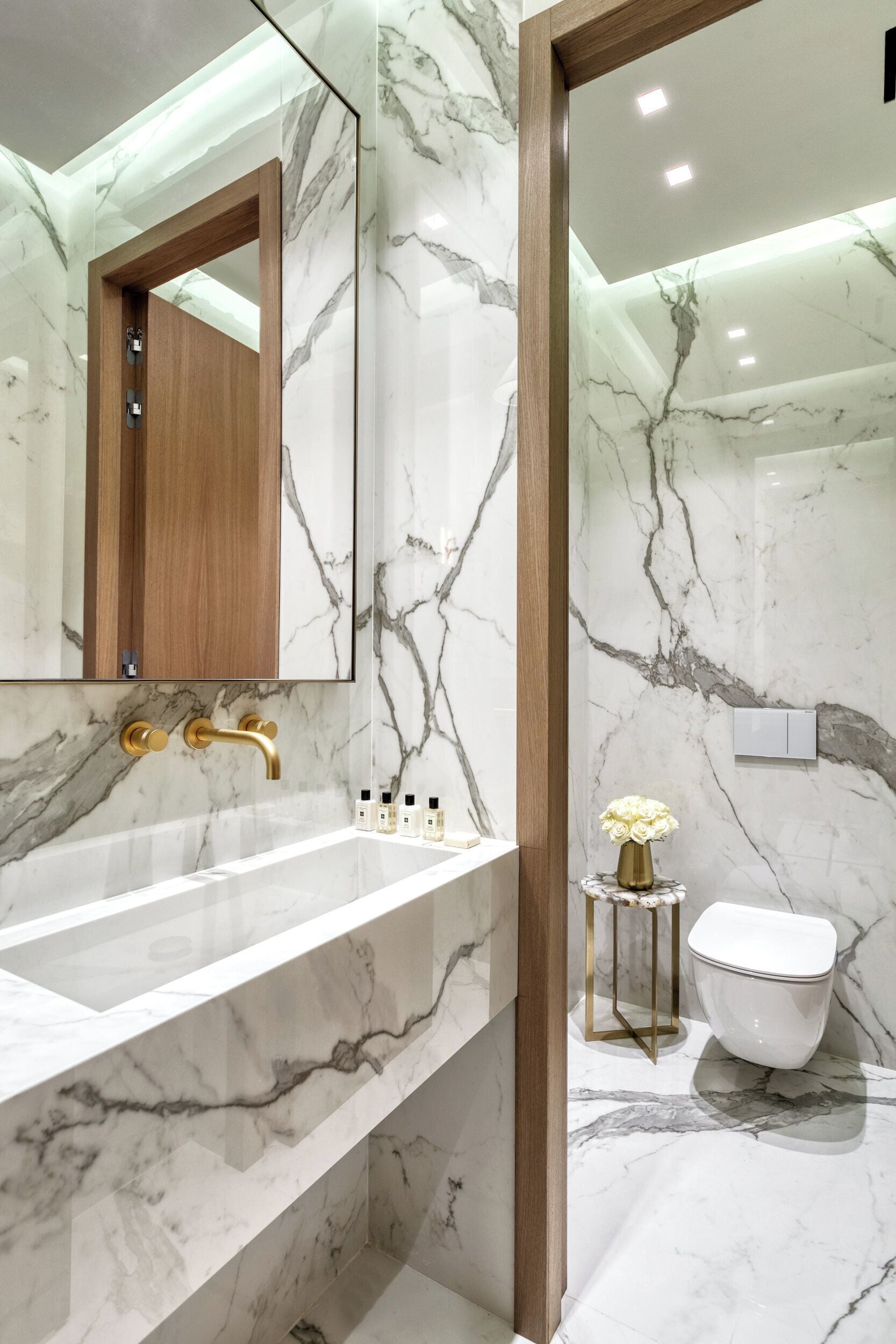 A bathroom with a marble sink, a wooden cabinet, and a toilet.