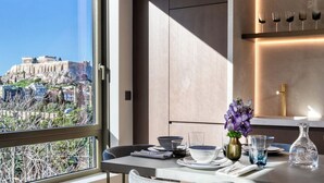 Un comedor moderno con vistas a Atenas, que presenta una mesa dispuesta con platos, vasos y un jarrón de flores.