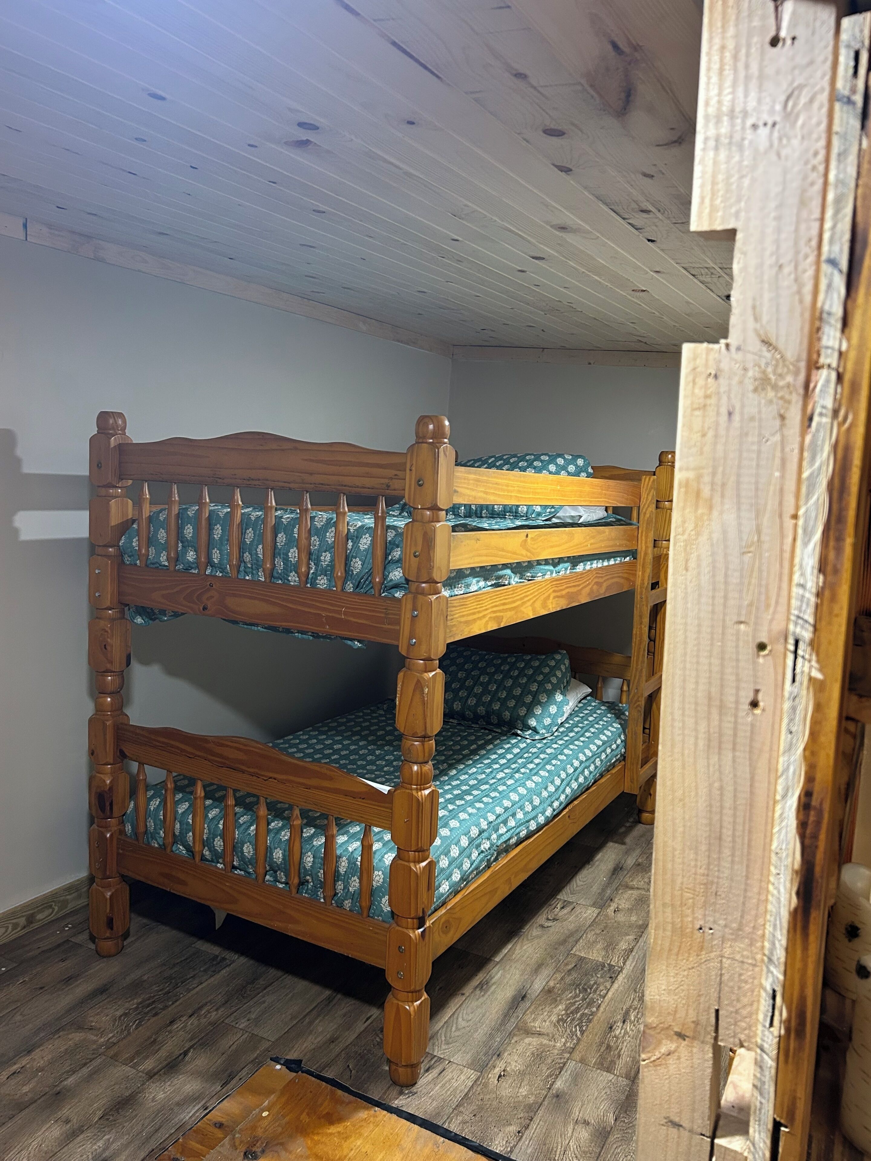 A bunk bed with a wooden frame and patterned bedding.