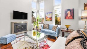 Een moderne woonkamer met een flatscreen televisie, een bank, een salontafel en kunstwerken aan de wanden.