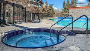 Un área de piscina con un jacuzzi, otra piscina y un muro de piedra.