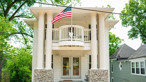 A two-story house with a balcony, stone pillars, and an American flag. - Downtown Historic Loop Downstairs Queen Free Parking (Eureka Springs)