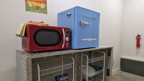 A kitchenette with a microwave, a blue refrigerator, and a metal shelf with kitchenware. - Downtown Historic Loop Downstairs Queen Free Parking (Eureka Springs)