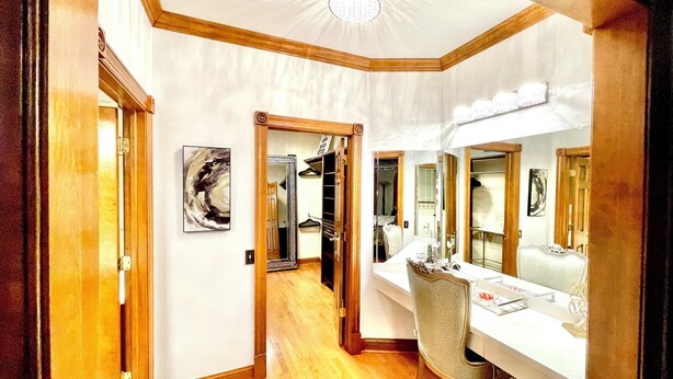 A hallway with a wooden floor, a white wall, and a ceiling with a central light fixture. There is a door on the left and a mirror on the right. - Huge Farmstay w/ Pool, Animals, Pond, Event Barn, & Clubhouse w/ Game Room (La Plata)