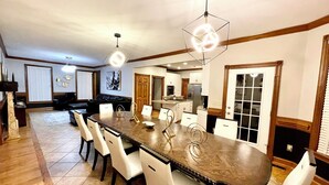 A spacious dining area with a large wooden table, white chairs, and pendant lighting. - Huge Farmstay w/ Pool, Animals, Pond, Event Barn, & Clubhouse w/ Game Room (La Plata)