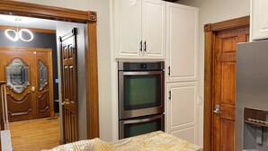 A kitchen with white cabinets, a stainless steel oven, and a wooden door with glass panels. - Huge Farmstay w/ Pool, Animals, Pond, Event Barn, & Clubhouse w/ Game Room (La Plata)