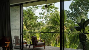 A room with a large sliding glass door leading to a balcony with a view of lush greenery. - Villa Alba (Ahangama)