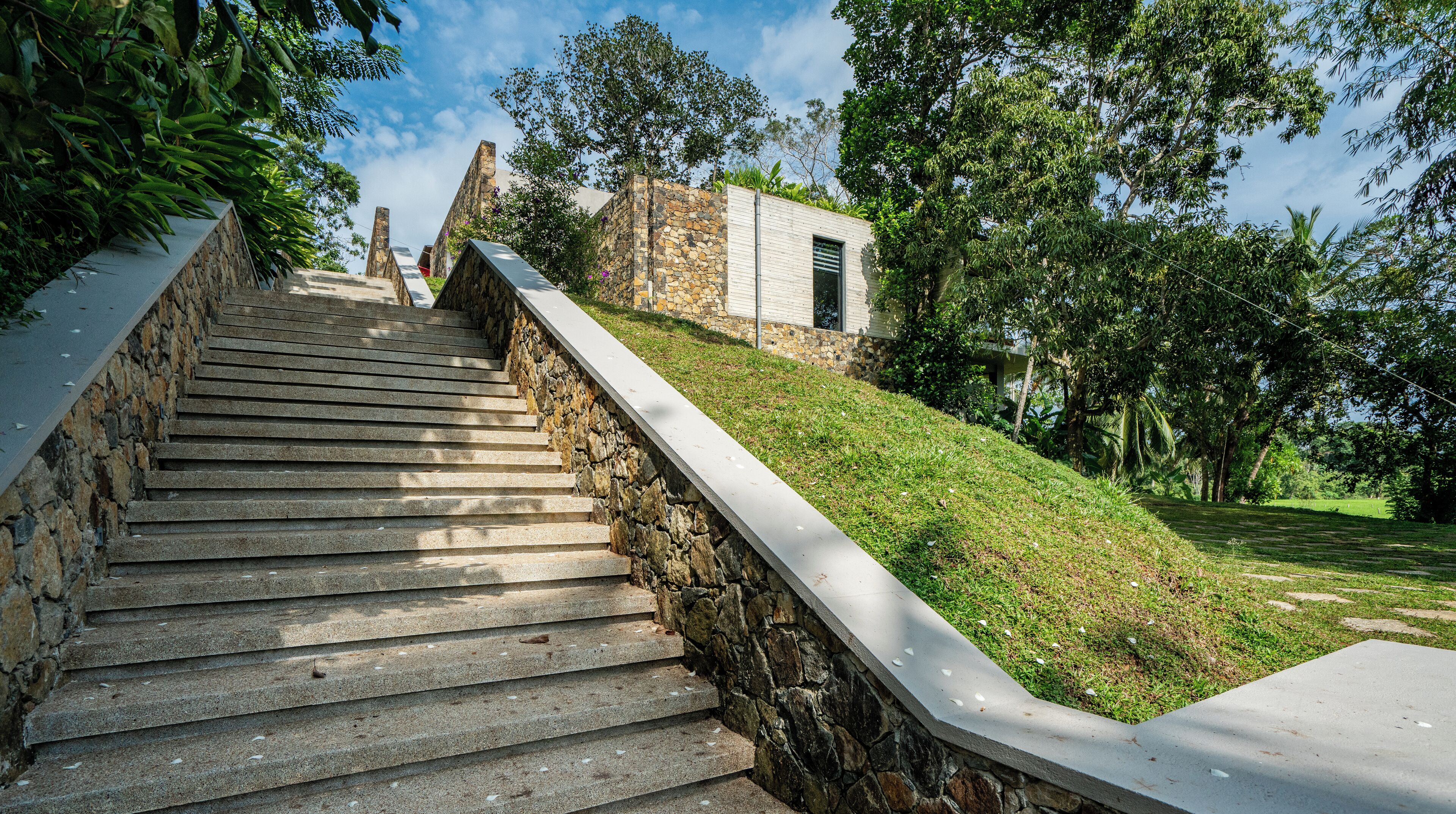 A stone staircase leading up to a building with a stone facade and a small window.