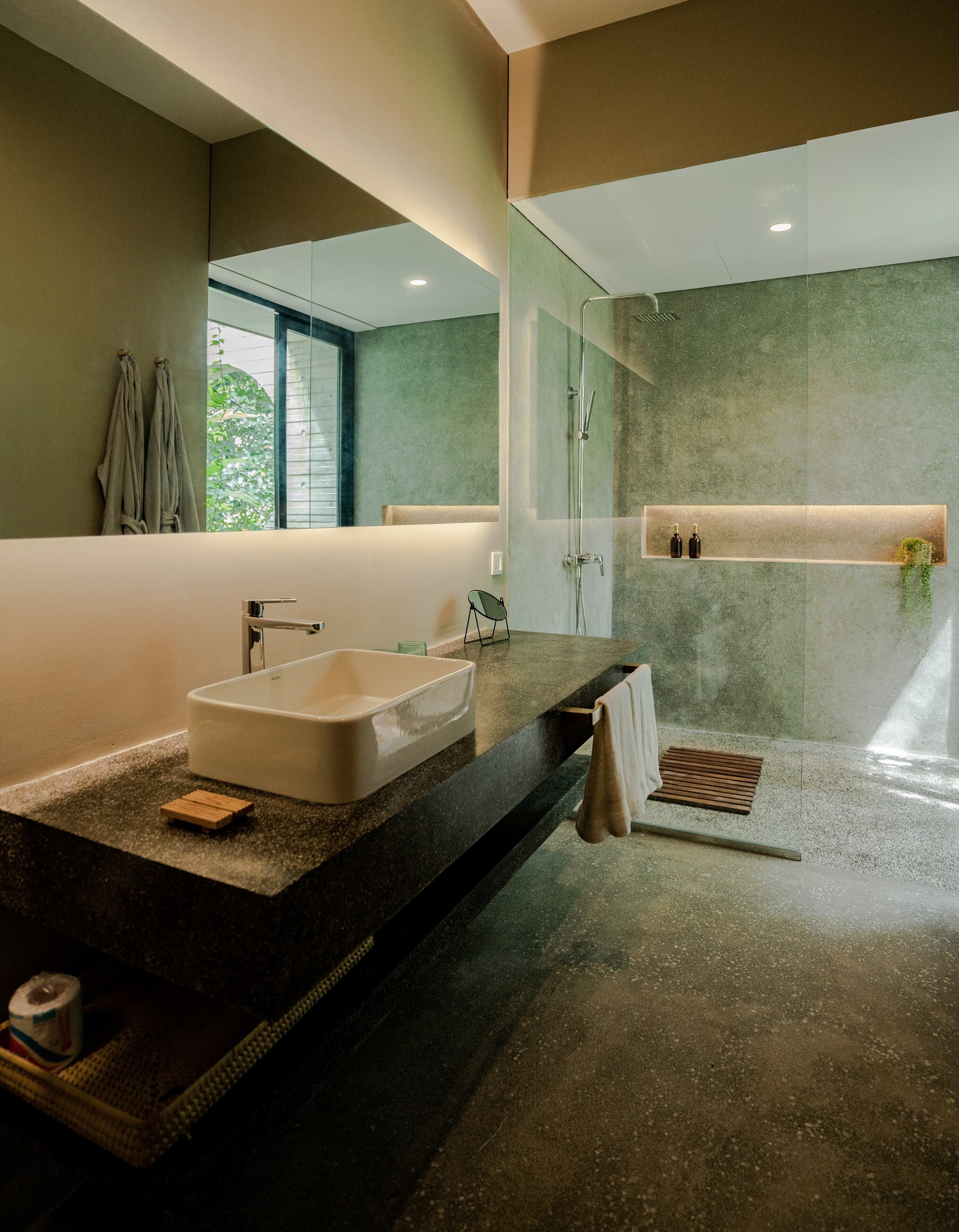 A modern bathroom with a large mirror, a bathtub, a shower, and a vanity with a sink.