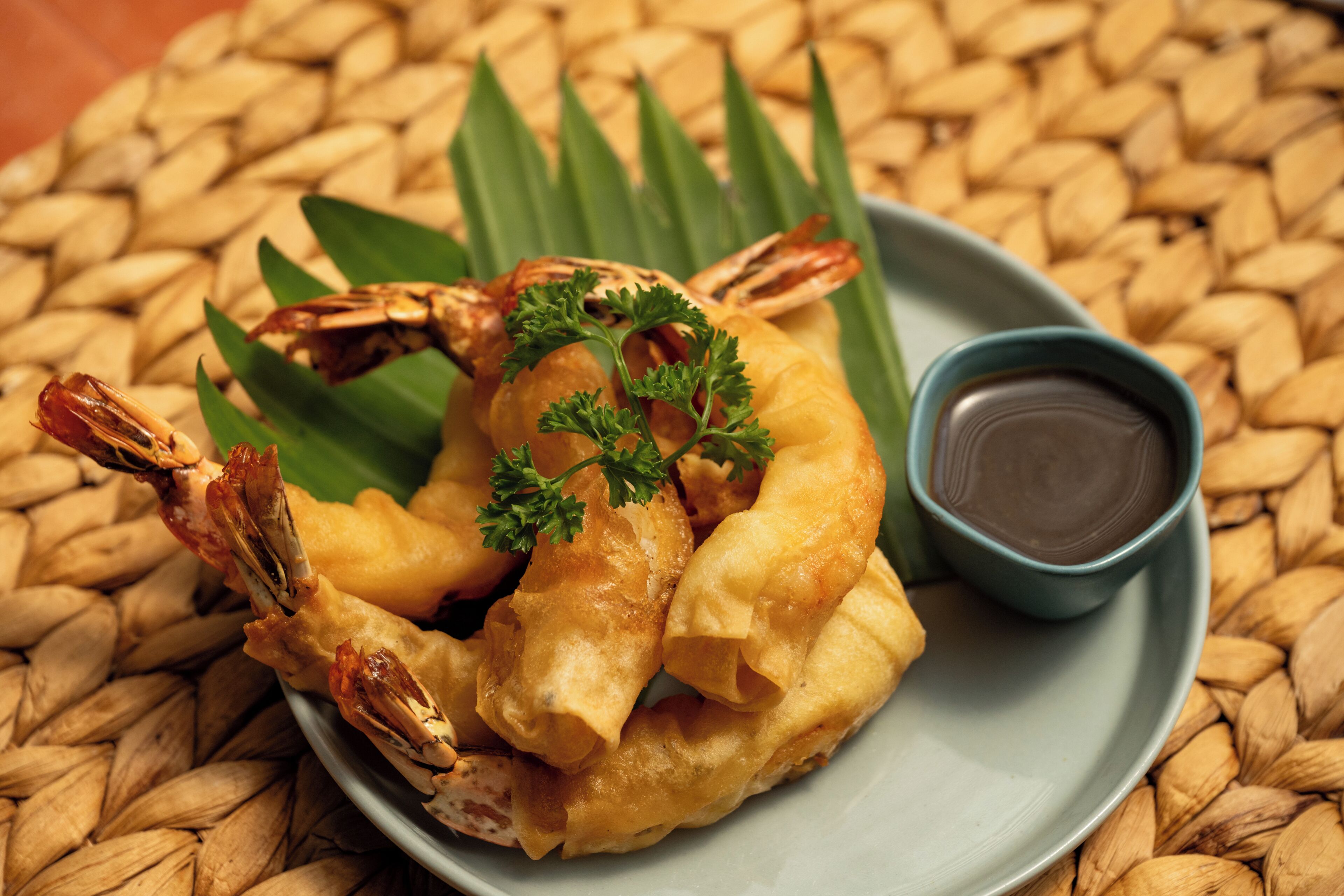 A plate of fried seafood with a dipping sauce and garnishes.