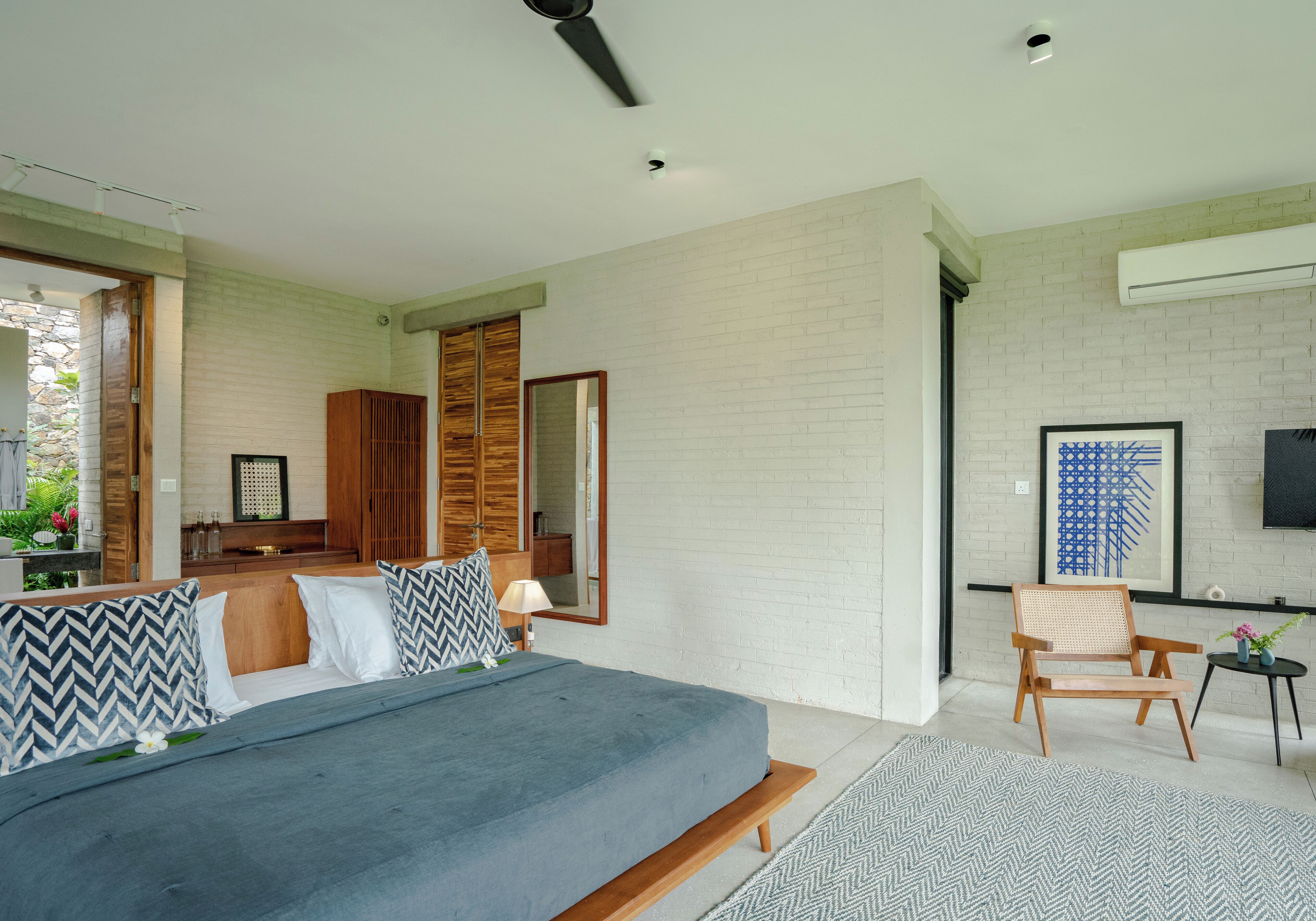 A modern bedroom with a bed, wooden headboard, and a large mirror.