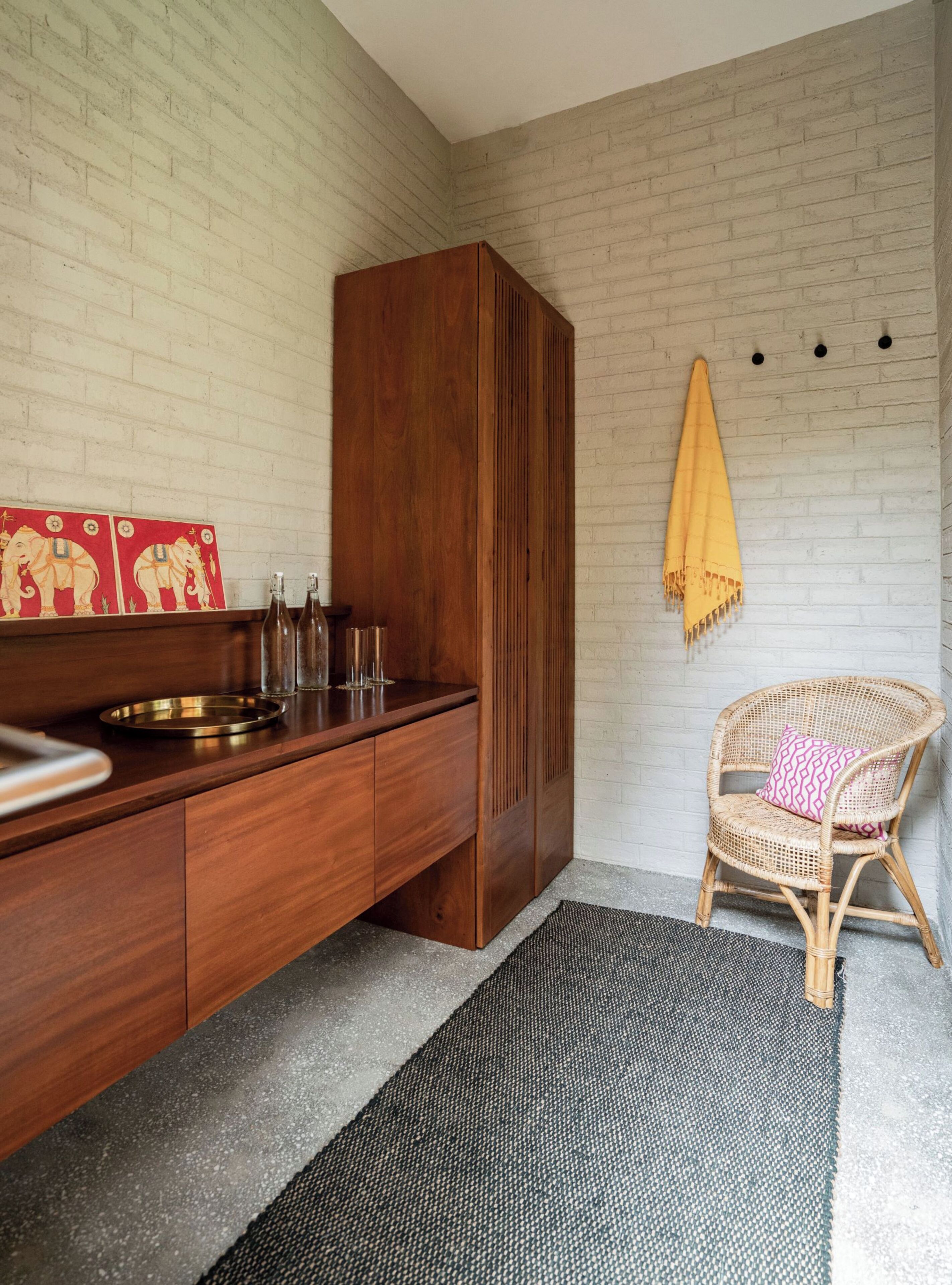 A modern kitchen with a wooden cabinet, a wicker chair, and a yellow towel on the wall.