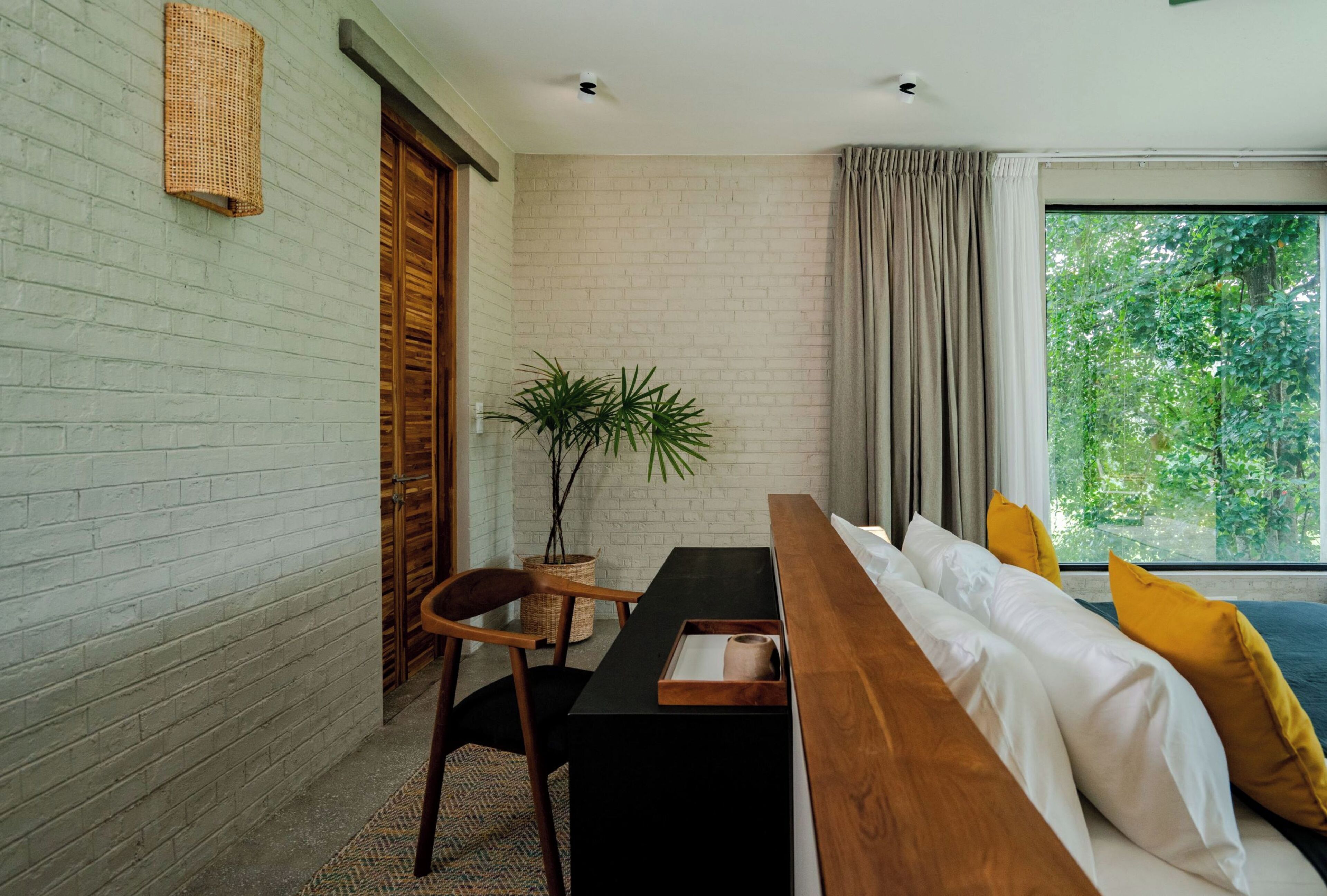 A modern room with a wooden bench, a potted plant, and a view of greenery through the window.