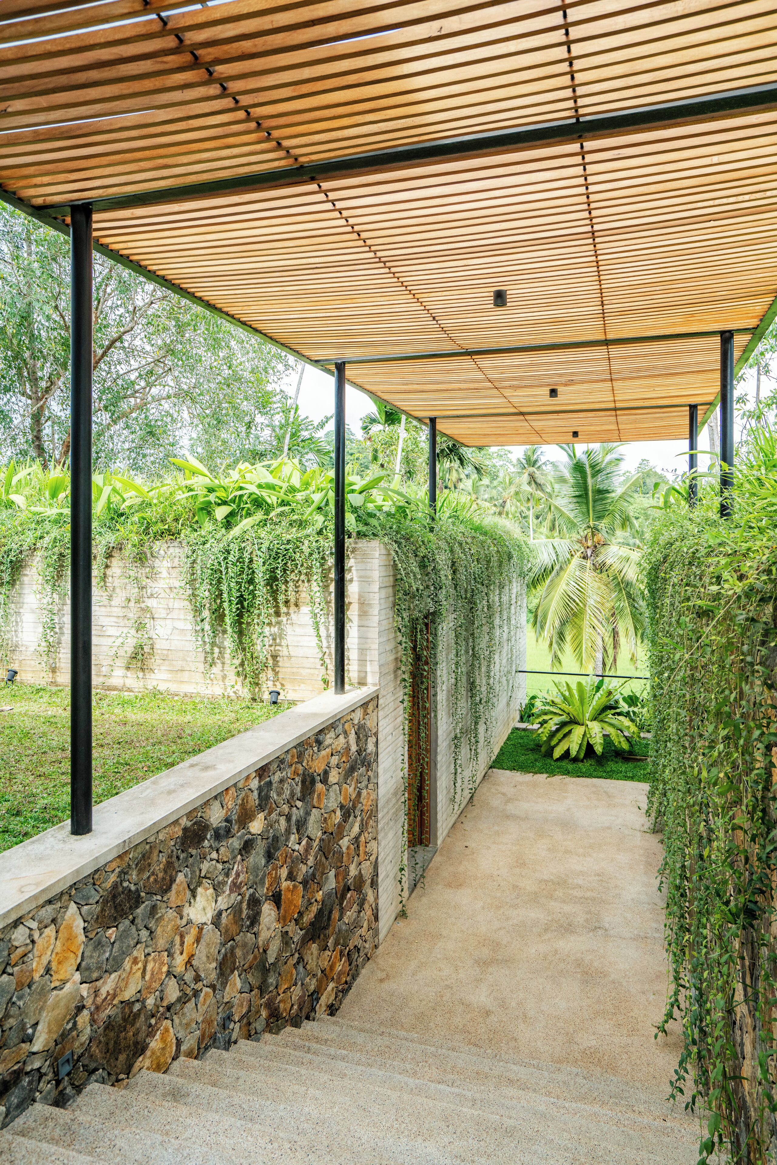 A covered outdoor pathway with stone walls and greenery.