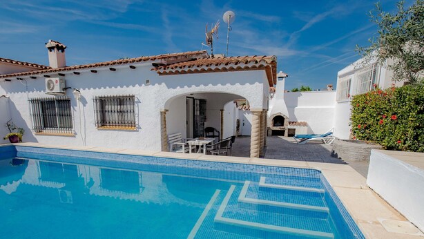 Une villa blanche dotée d’une piscine, d’un espace salon extérieur et d’un toit recouvert de tuiles.