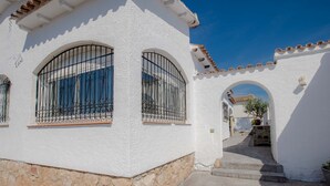Un bâtiment blanc doté de fenêtres en arc de cercle et d’un socle en pierre.