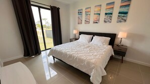Camera da letto con un letto grande, un comodino, una lampada e vista sull'esterno tramite una porta scorrevole.