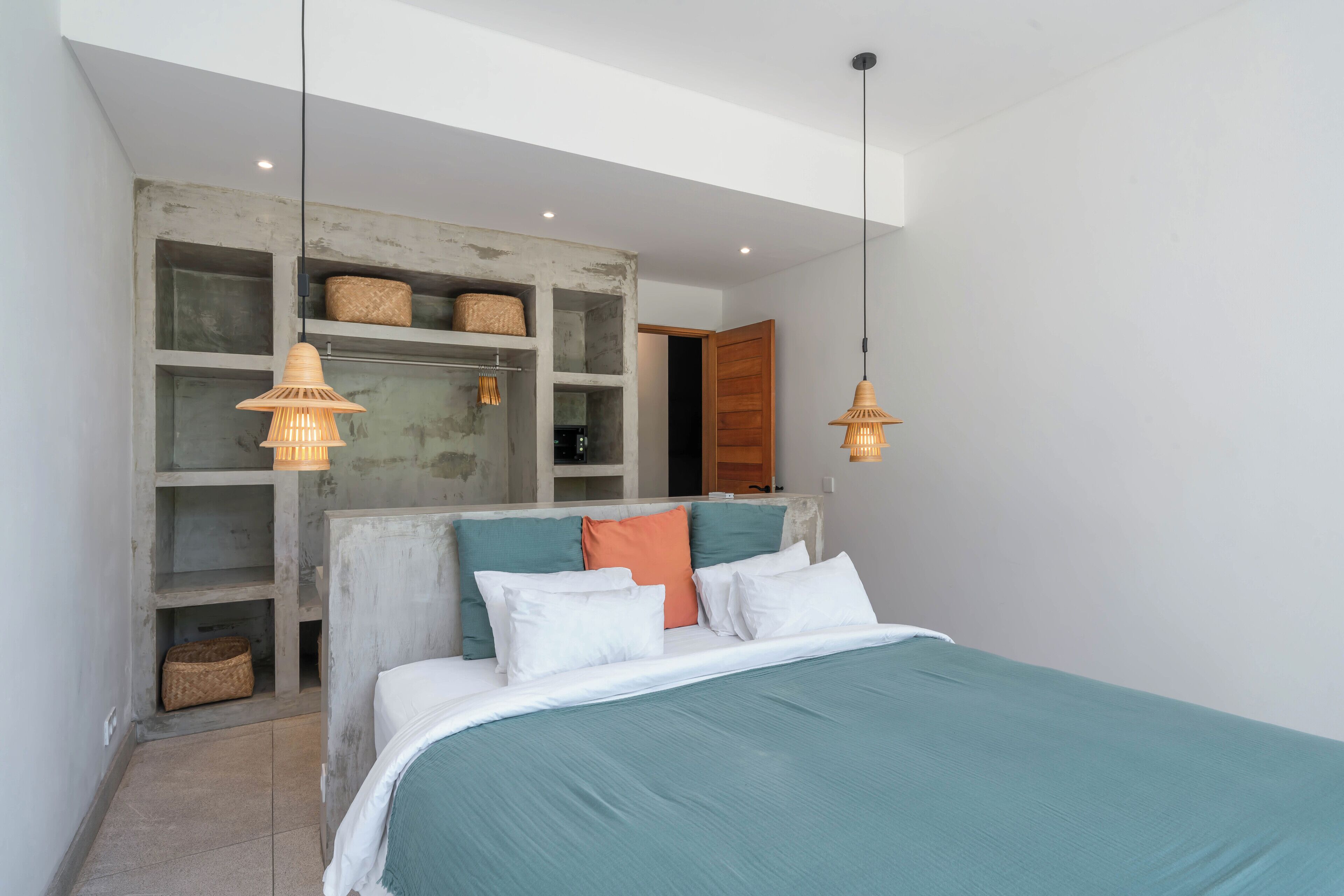 A bedroom with a bed, built-in shelving, and pendant lighting.