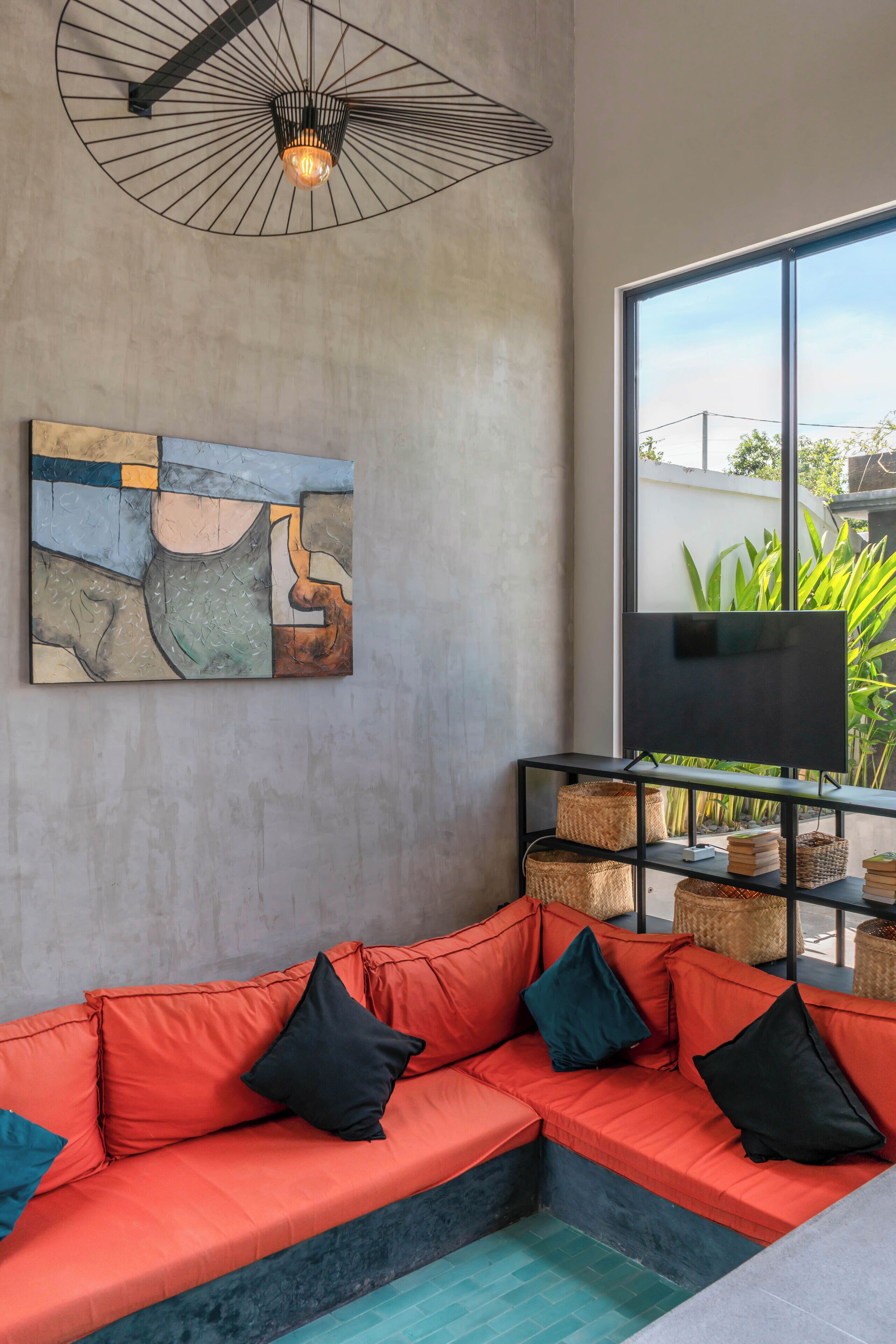 Una sala de estar moderna con un sofá modular, un televisor de pantalla plana, una obra de arte contemporánea y una lámpara en el techo.